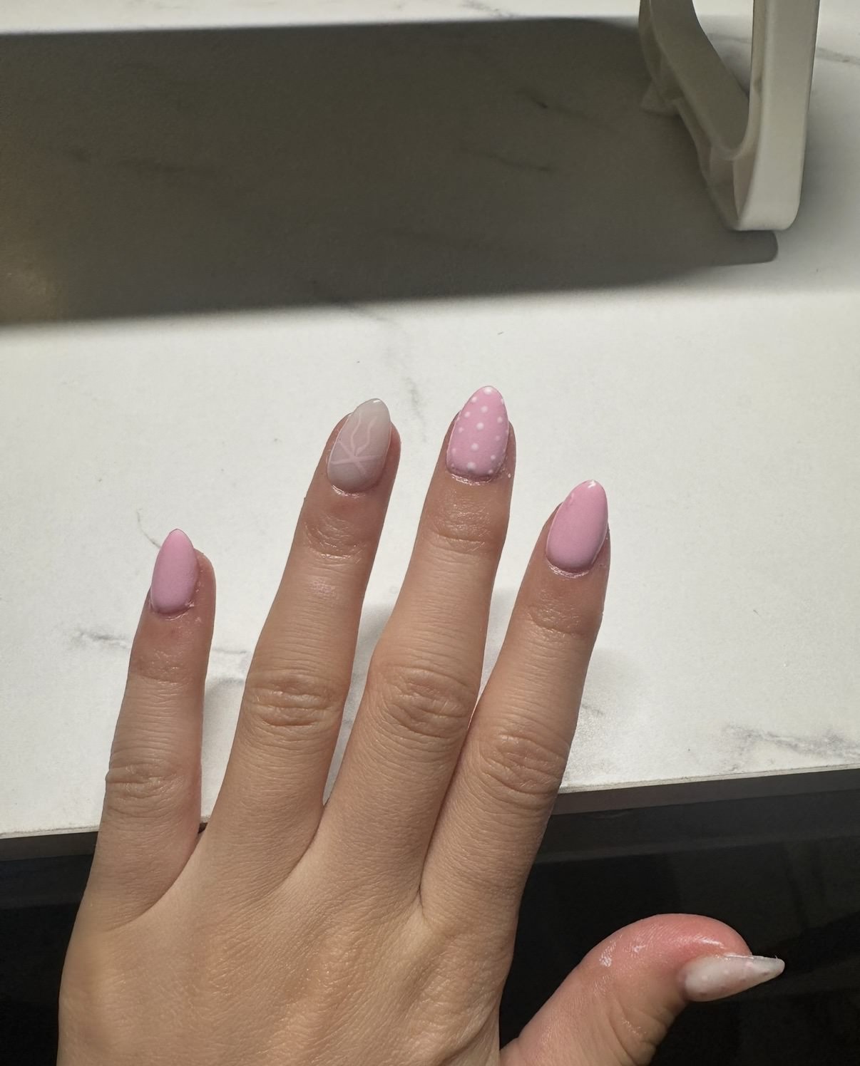 Pink gel manicure detail by Raegan with soft polka dots and delicate bow artwork